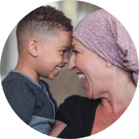 Smiling boy and woman with scarf on head touching foreheads