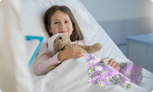 Young girl in hospital bed holding teddy bear