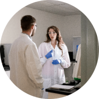 Male and female scientific staff in gloves and safety glasses talking in office